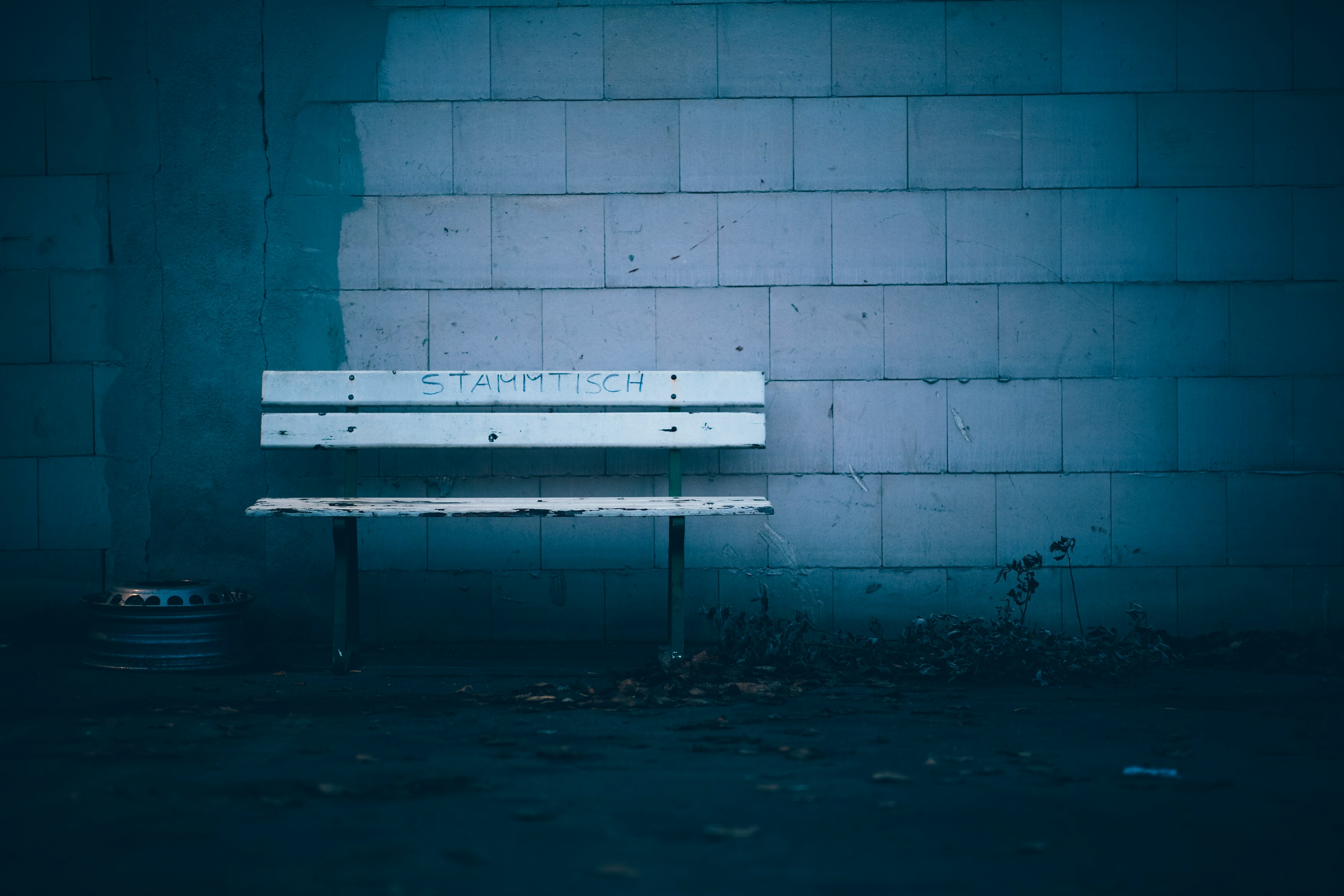 white wooden bench beside blue brick wall